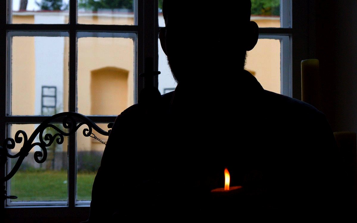 silueta člověka u okna, tma, plamen svíce / foto Michal Němeček
