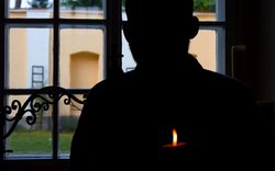 silueta člověka u okna, tma, plamen svíce / foto Michal Němeček
